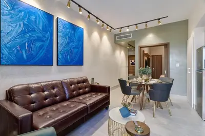 a living room with a leather couch and a table at Modern Comfort Apartment at Bella Vista in Santo Domingo