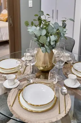 a table with plates and glasses and a vase with flowers at Modern Comfort Apartment at Bella Vista in Santo Domingo