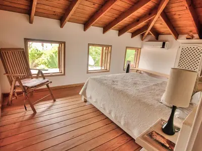 a bedroom with a bed and a chair and windows at Villa Ibiscus in Las Galeras