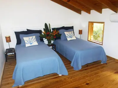 a bedroom with two beds with blue sheets and a window at Villa Ibiscus in Las Galeras