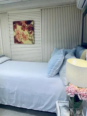 a bed with white sheets and blue pillows in a room at Feair in Santo Domingo