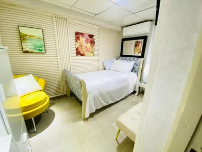 a small bedroom with a bed and a yellow chair at Jacqueline in Santo Domingo