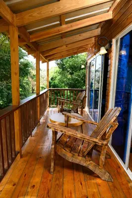 a porch with two rocking chairs on a wooden deck at villas ecologicas hacienda vista linda in Cabrera