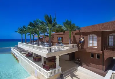 a woman standing on the balcony of a building next to the ocean at Villa Tranquila - Sosua Ocean Village in Sosúa
