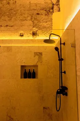 a bathroom with a shower with three bottles on a shelf at Casa Grullon, an Oasis in the Colonial Zone in Santo Domingo