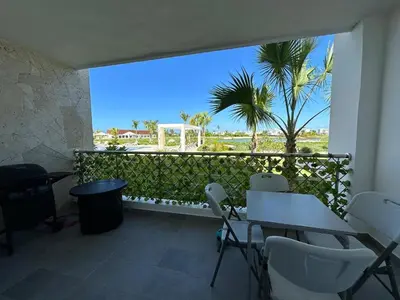 a balcony with a table and chairs and a palm tree at Las Cañas Playa Nueva Romana in El Soco
