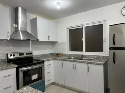 a kitchen with white cabinets and black appliances at Las Cañas Playa Nueva Romana in El Soco