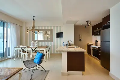 a kitchen and living room with a table and chairs at Escape Beachfront Condos Las Olas Juan Dolio in La Puntica de Juan Dolio