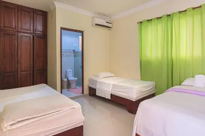 a bedroom with two beds and a green curtain at Apartahotel Santo Domingo EsteRD - Aeropuerto Las Americas in La Viva