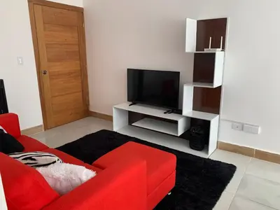 a living room with a red couch and a flat screen tv at Juan Bosch apartament in Santo Domingo