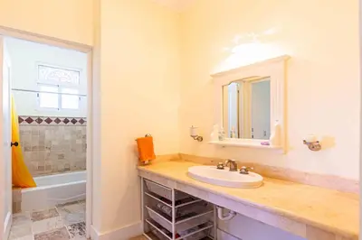a bathroom with a sink and a mirror and a tub at Oceanfront Apartment in Cabarete with Pool and Beach Access in Cabarete