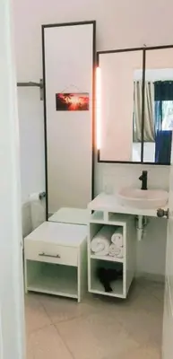 a white bathroom with a sink and a mirror at Apartment mit Meerblick direkt an der Playa Popy in Las Terrenas