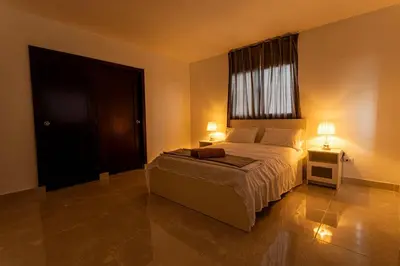 a bedroom with a bed with two lamps and a window at America Apartment in Santo Domingo