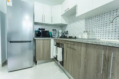 a kitchen with wooden cabinets and a stainless steel refrigerator at America Apartment in Santo Domingo