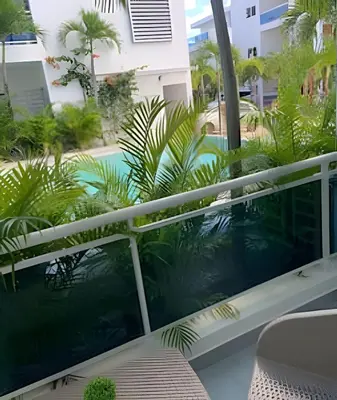a balcony with a swimming pool and palm trees at Bayahibe Rose C - Gray Elegance in San Rafael del Yuma
