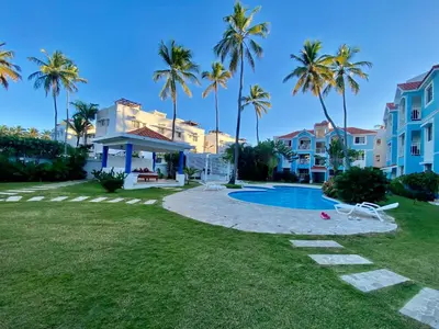 a villa with a swimming pool and palm trees at Fantástico Lugar en el Centro de los Corales RD in Punta Cana