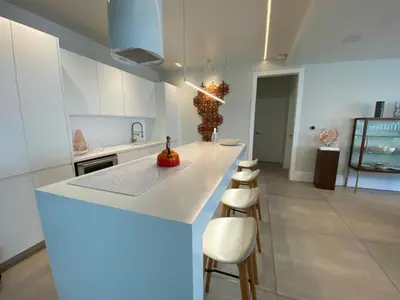 a white kitchen with a counter and stools in it at Hermoso apartamento en el centro de la coudadt in Santo Domingo