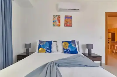 a bedroom with a large white bed with blue pillows at Gorgeous Banana Places QDA-IV in Santo Domingo