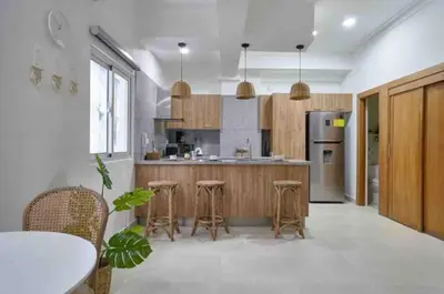 a kitchen with wooden cabinets and a table and stools at Natural Boho Places QDA-III in Santo Domingo
