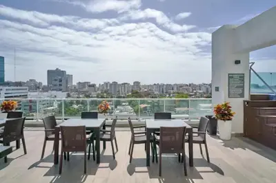 a balcony with tables and chairs and a view of the city at Natural Boho Places QDA-III in Santo Domingo