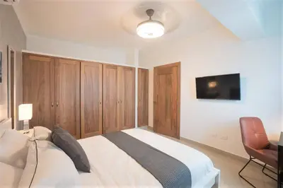 a bedroom with a bed with wooden cabinets and a television at Luxury and Cozy Places QDA-II in Santo Domingo