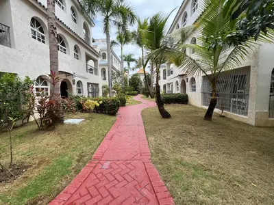 a brick walkway in front of a building with palm trees at Cozy Condo - 4 min to the Beach in Punta Cana