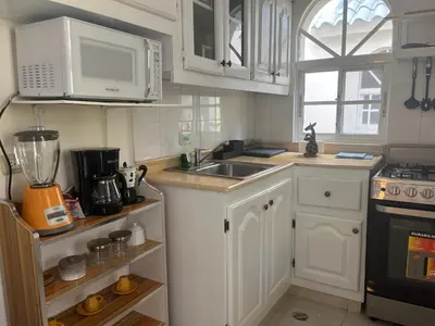 a kitchen with white cabinets and a sink and a microwave at Cozy Condo - 4 min to the Beach in Punta Cana