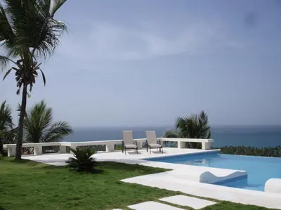a pool with two chairs and the ocean in the background at Villa with Stunning Ocean View, Infinity pool in Las Terrenas