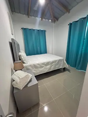 a bedroom with a bed and blue curtains at Apartamento Media Luna in Cabrera