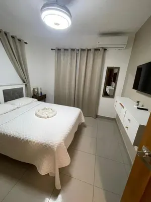 a bedroom with a white bed and a television at Exclusive Luxury Apartment with Pool in Santiago de los Caballeros