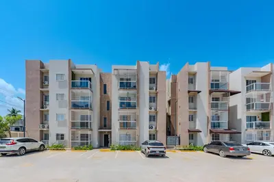 a large apartment building with cars parked in a parking lot at Oasis cerca del mar #2 in Monte Adentro