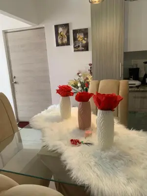 two vases with red roses in them on a table at habitat 1 t4 101 ciudad juan Bosch in San Isidro