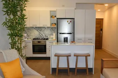 a kitchen with a white counter and a refrigerator at Perla Marina Beach Condo- Walk to Yoga, Spa & Food in Sosúa