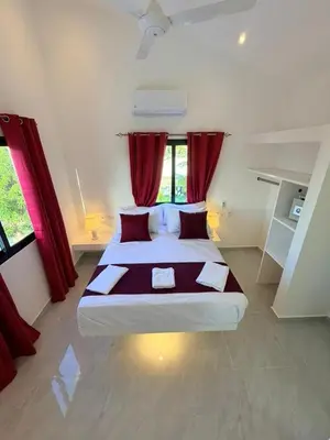 a bedroom with a large bed with red curtains at Taina village in Las Terrenas