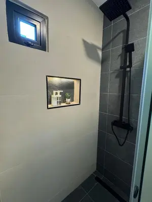 a bathroom with a shower with a television on the wall at Heyday Studio With Full Kitchenette in Santiago de los Caballeros