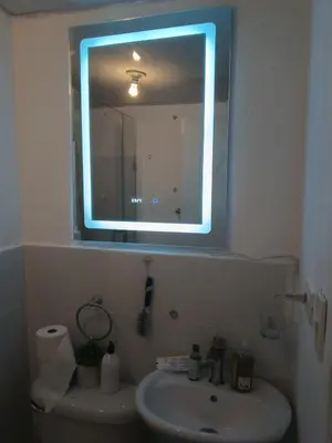 a bathroom with a sink and a mirror with a light at Cómodo Apartamento en Santiago in Santiago de los Caballeros