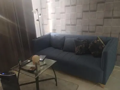 a living room with a blue couch and a table at Cómodo Apartamento en Santiago in Santiago de los Caballeros