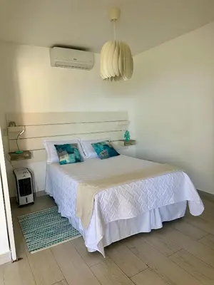 a white bedroom with a white bed with blue pillows at Apartamento lll Vista al Mar Albatros by ju Juan Dolio in Villas del Mar