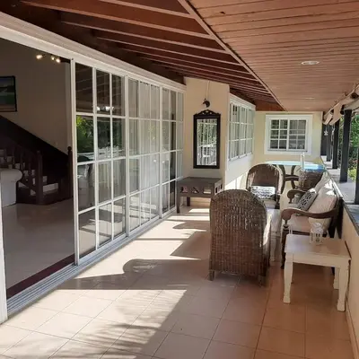 a screened porch with wicker chairs and a table at Beautiful, fresh peaceful Villa in Sosúa