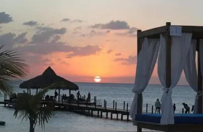 a sunset on the beach with people on a pier at Cadaques Bayahibe Beach Front in Bayahibe