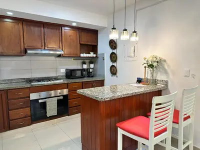 a kitchen with wooden cabinets and a red chair at a counter at Casa en la Autopista de San Isidro in Hainamosa