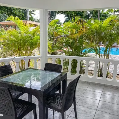 a glass table and chairs on a balcony with palm trees at Hotel Appartements Hummingbird CABARETE in Cabarete
