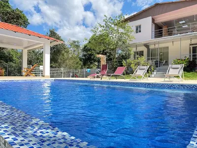 a swimming pool with two chairs and a house at villa el naciente in La Cuaba