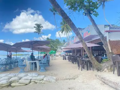 a beach with tables and chairs and umbrellas at Brisa de mar BOCA CHICA, in Boca Chica