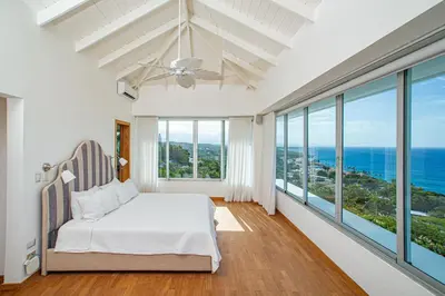 a bedroom with a bed and large windows at 5 mins from beach, Hilltop villa with pool in La Pared