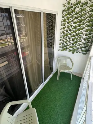 a screened porch with a chair and green carpet at Apartamento en ciudad Juan bosch con todas las amenidades in Los Paredones