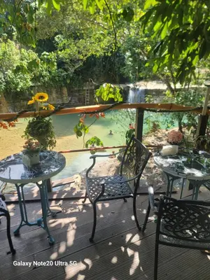 two tables and chairs on a deck with a view of a pond at Rancho Salto Yanigua in El Valle
