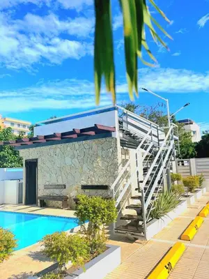a building with a staircase next to a swimming pool at Modern Apartment, Juan Dolio Beach, BlueSea Tower in Villas del Mar
