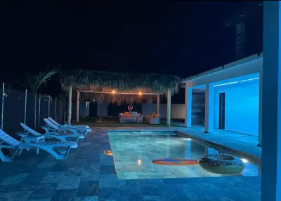 a swimming pool at night with chairs and a table at Apartamento Entre Playas 3 - 2 pax, 4 min de la playa in Las Galeras