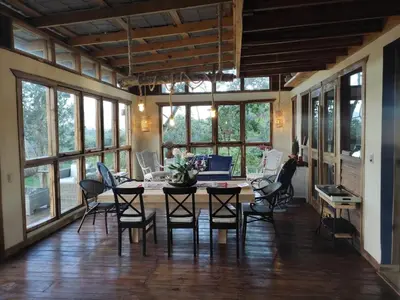 a dining room with a table and chairs and windows at MaRaVillas DR in the mountains excellent location in Jarabacoa